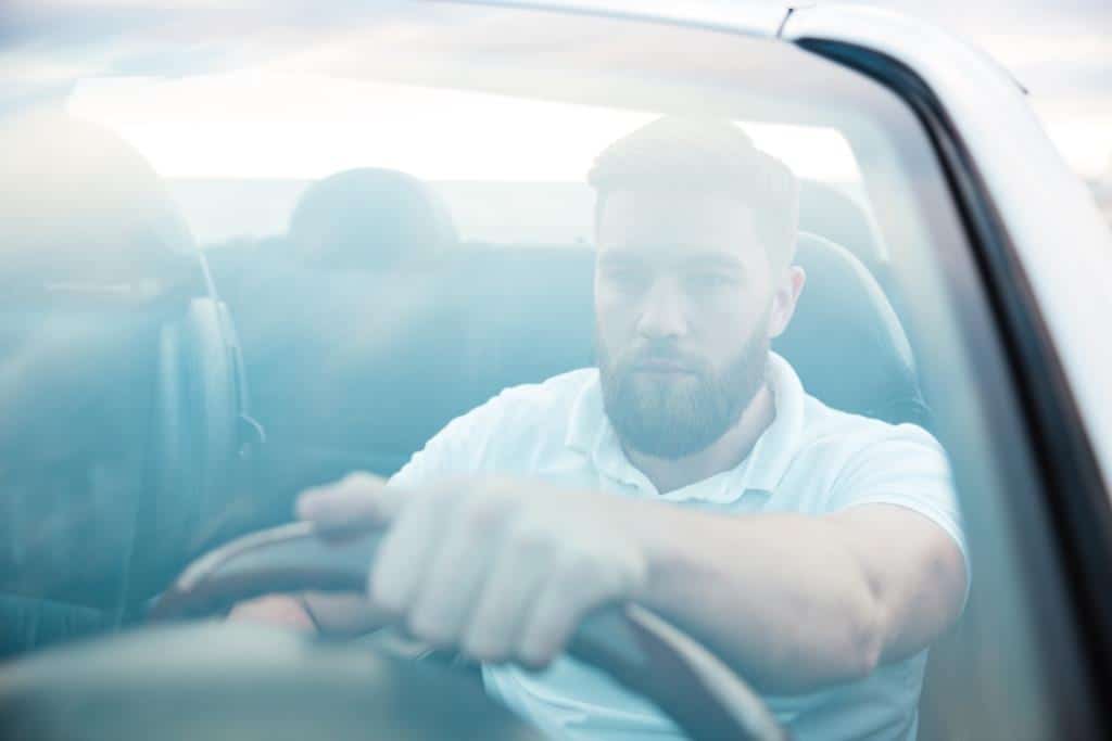 Handsome bearded man driving new car